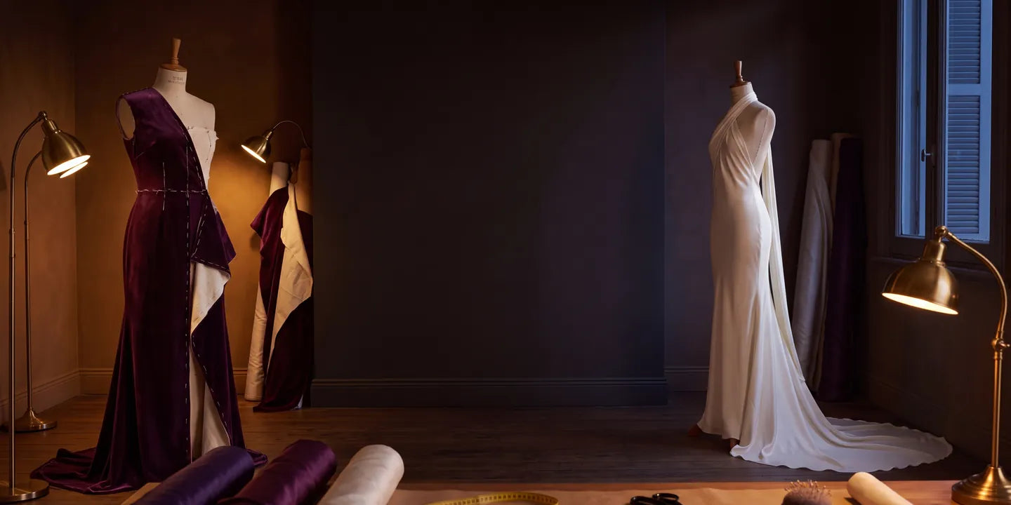 Taller de costura con dos vestidos en maniquí, telas y lámparas de bronce